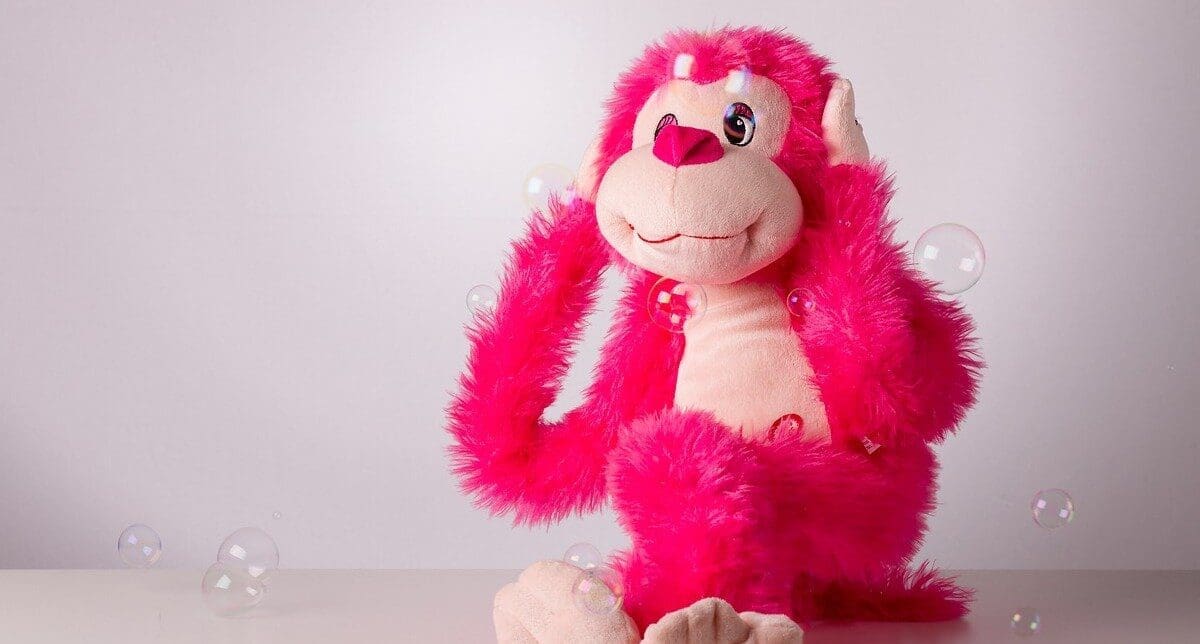 A plush, hot pink toy covering its ears A plush, hot pink toy covering its ears