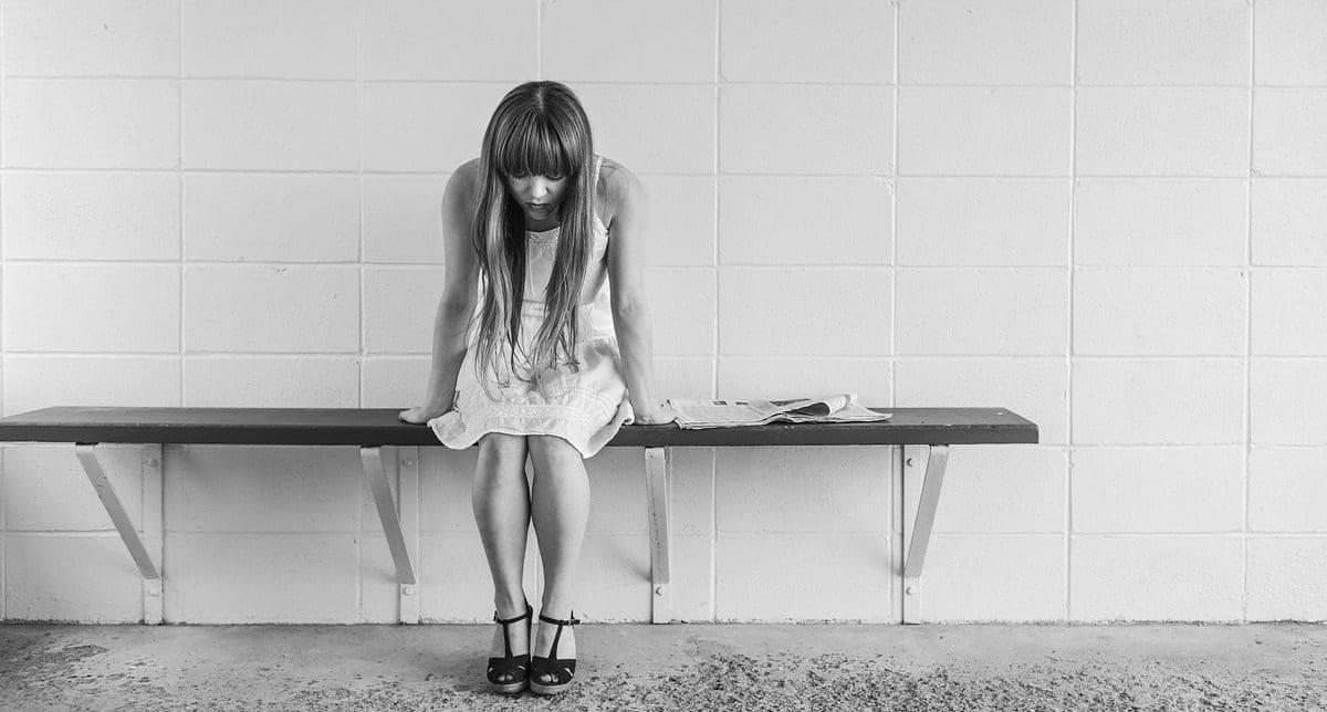 A young woman sitting alone on a bench and looking discouraged A young woman sitting alone on a bench and looking discouraged